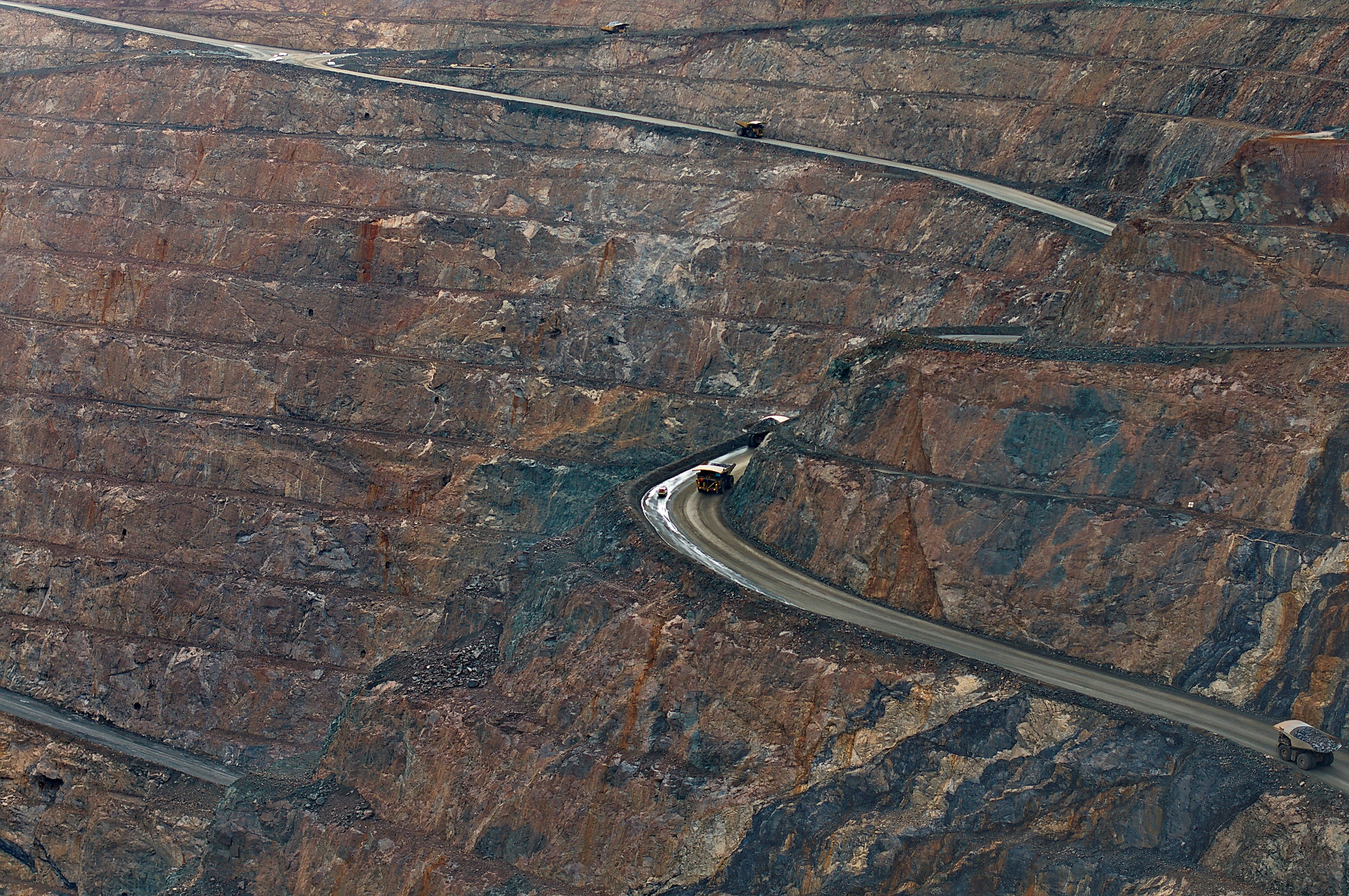 Aerial view of an open-pit iron ore mine with haul trucks on winding roads