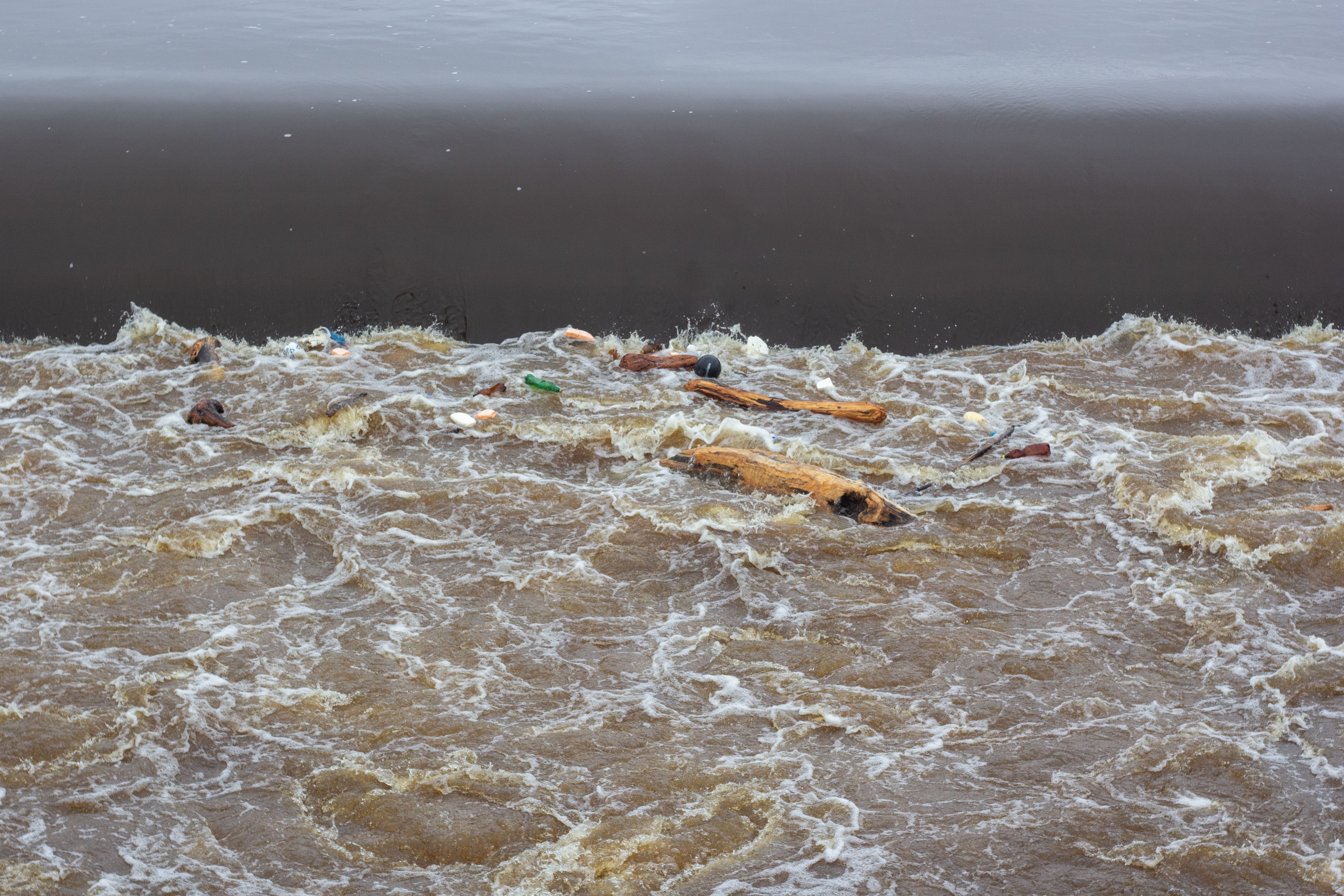 Polluted river with floating debris and turbid water showing the aftermath of mining contamination