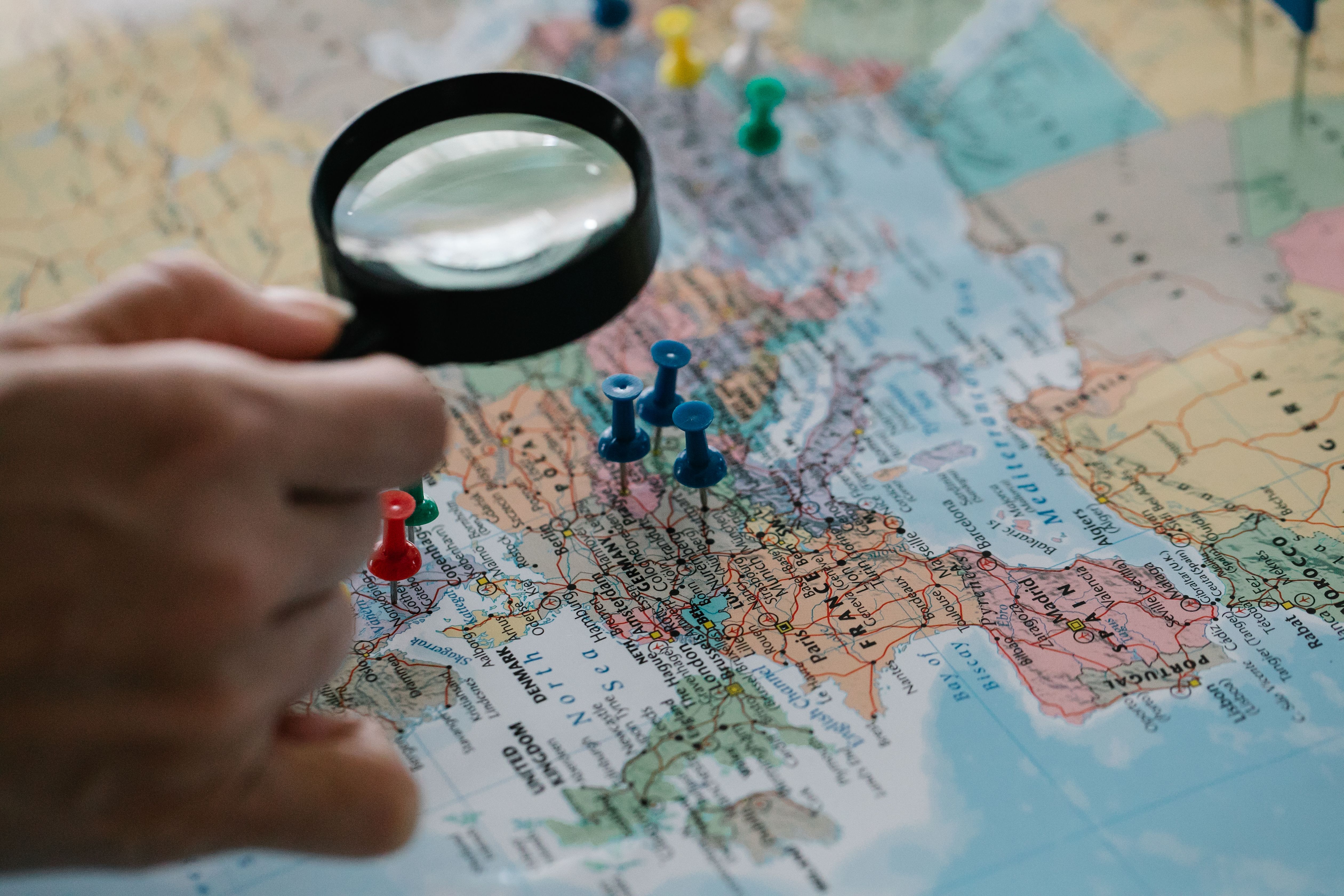 Magnifying glass marking locations on a world map to represent cross-border legal matters