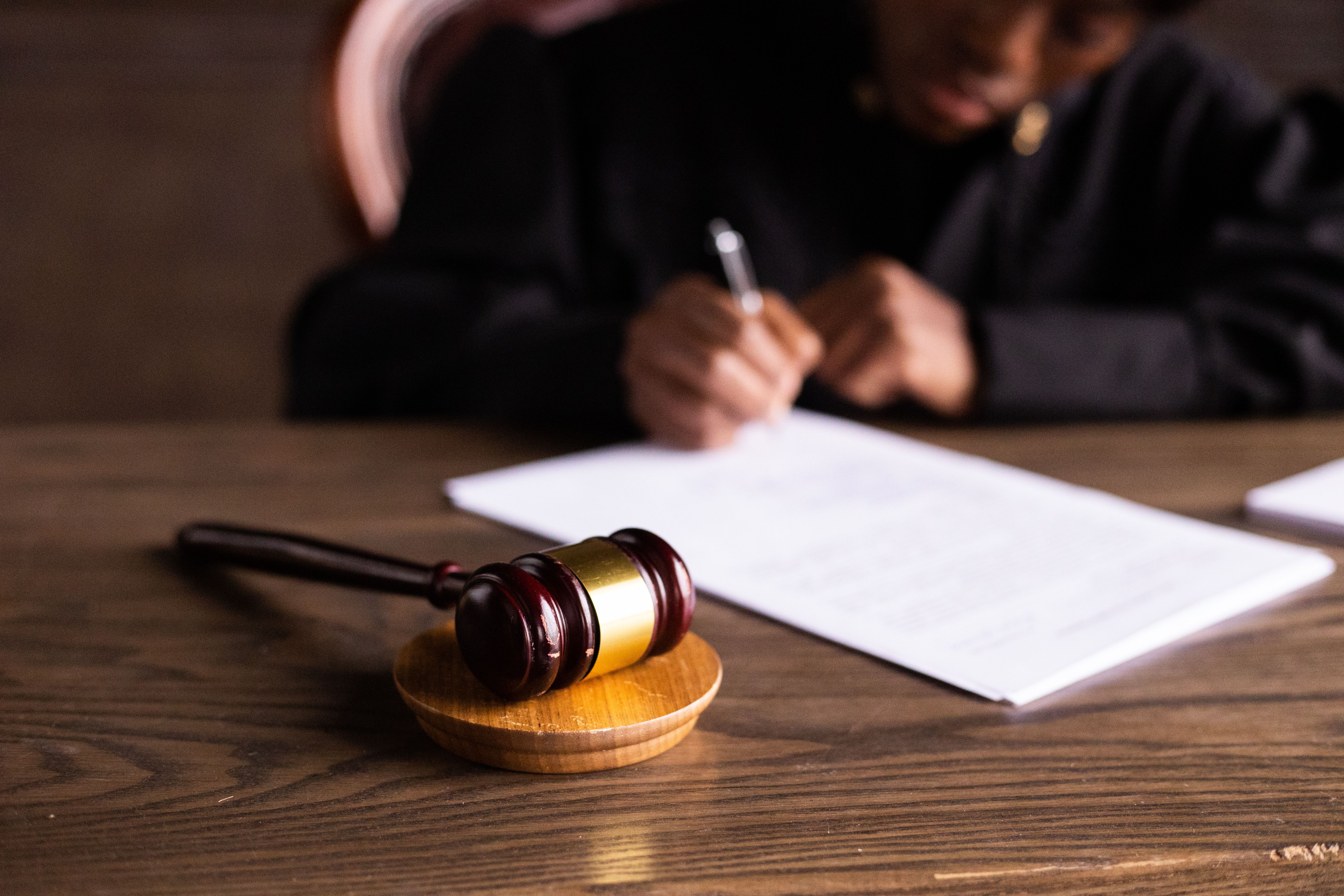 Legal professional signing documents beside a gavel, representing case resolution