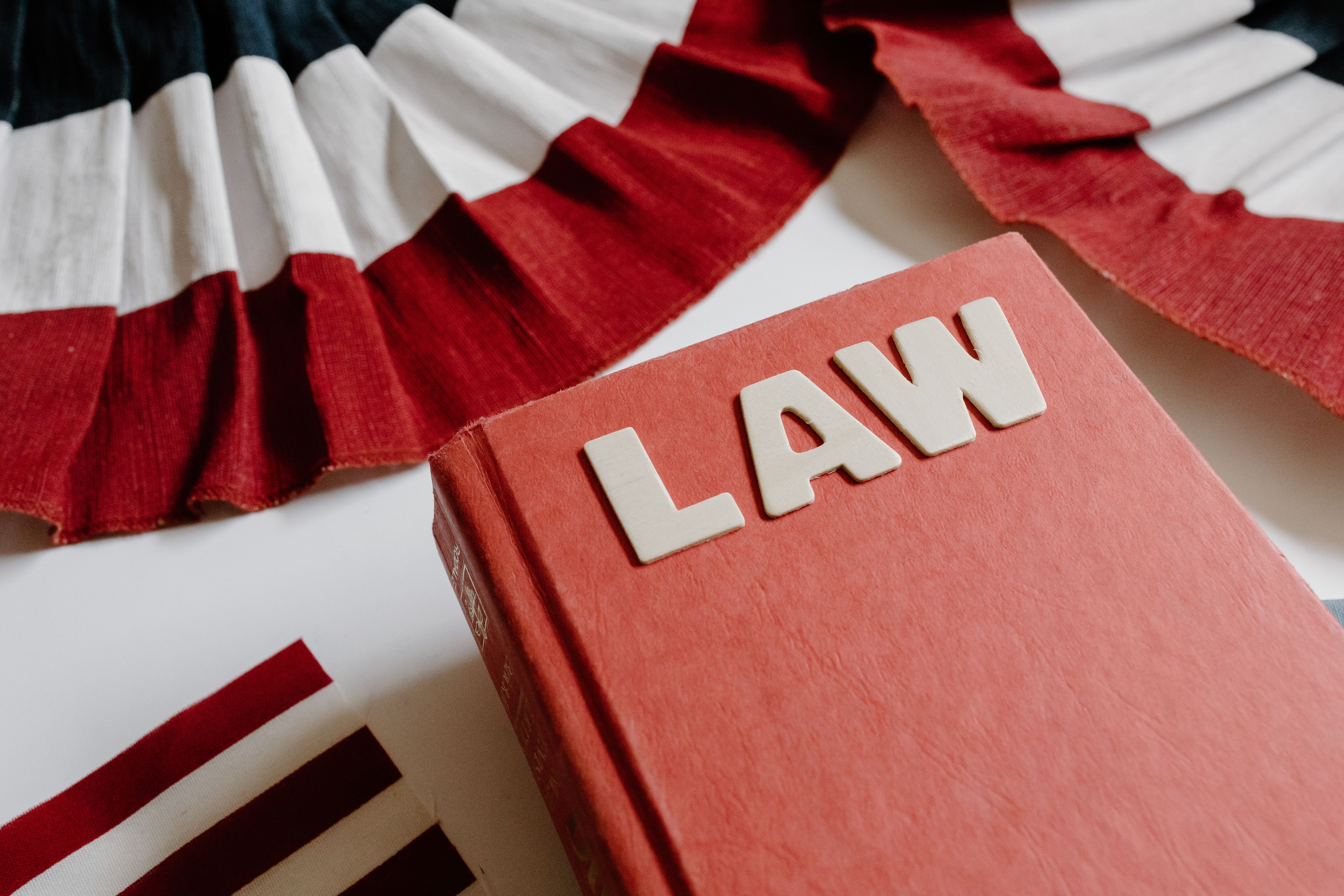 A law book with bold letters beside a red, white, and black decorative ribbon